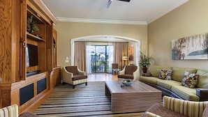 Un salón espacioso con un mueble grande de madera, dos sillones, un sofá y una mesa de centro.