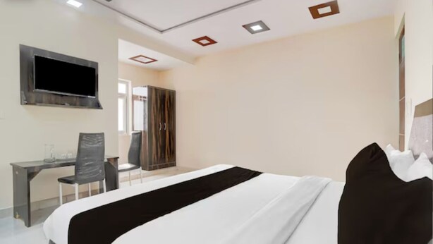 A hotel room with a bed, a desk, a chair, and a TV mounted on the wall. - Hotel O Taj Holiday  (Agra)