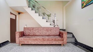 A lobby with a marble floor, a pink sofa, a staircase with metal railings, and a painting on the wall. - Hotel O Taj Holiday  (Agra)