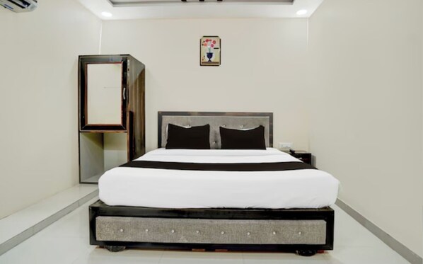 Une chambre d’hôtel moderne avec un grand lit, une armoire et une petite table.