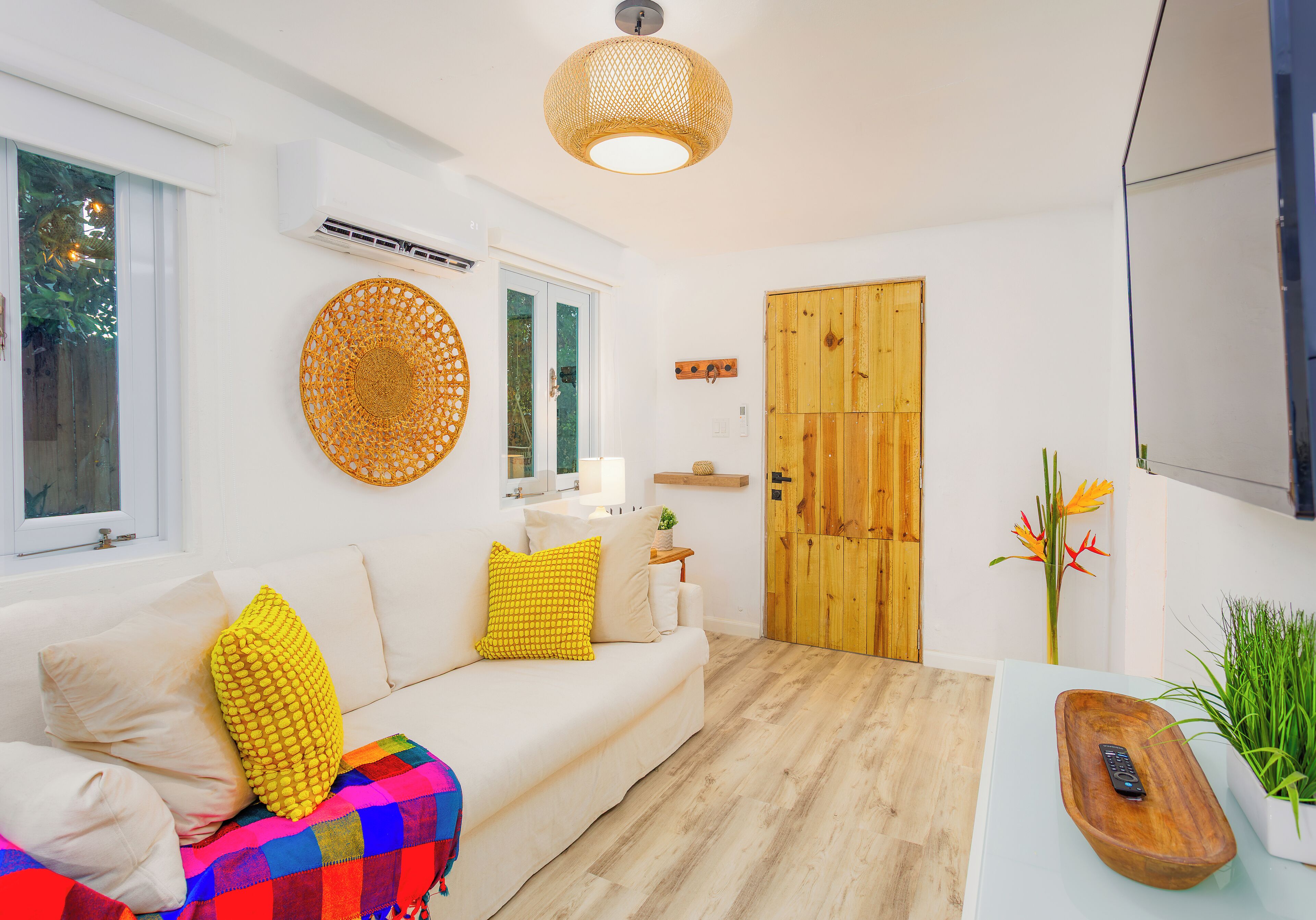 Un salon moderne avec un canapé blanc, un plaid coloré et une porte en bois.