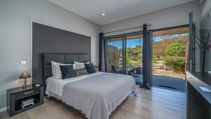 Een moderne slaapkamer met een groot bed, een nachtkastje en uitzicht op de omgeving.