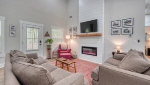 Ein Wohnzimmer mit Kamin, Sofas, einem Couchtisch und einem an der Wand befestigten Fernseher.