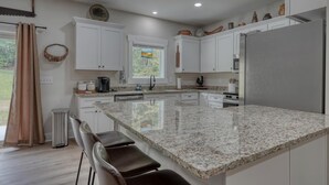 Eine moderne Küche mit weißen Schränken, Granit Arbeitsplatten und einem Edelstahl-Kühlschrank.