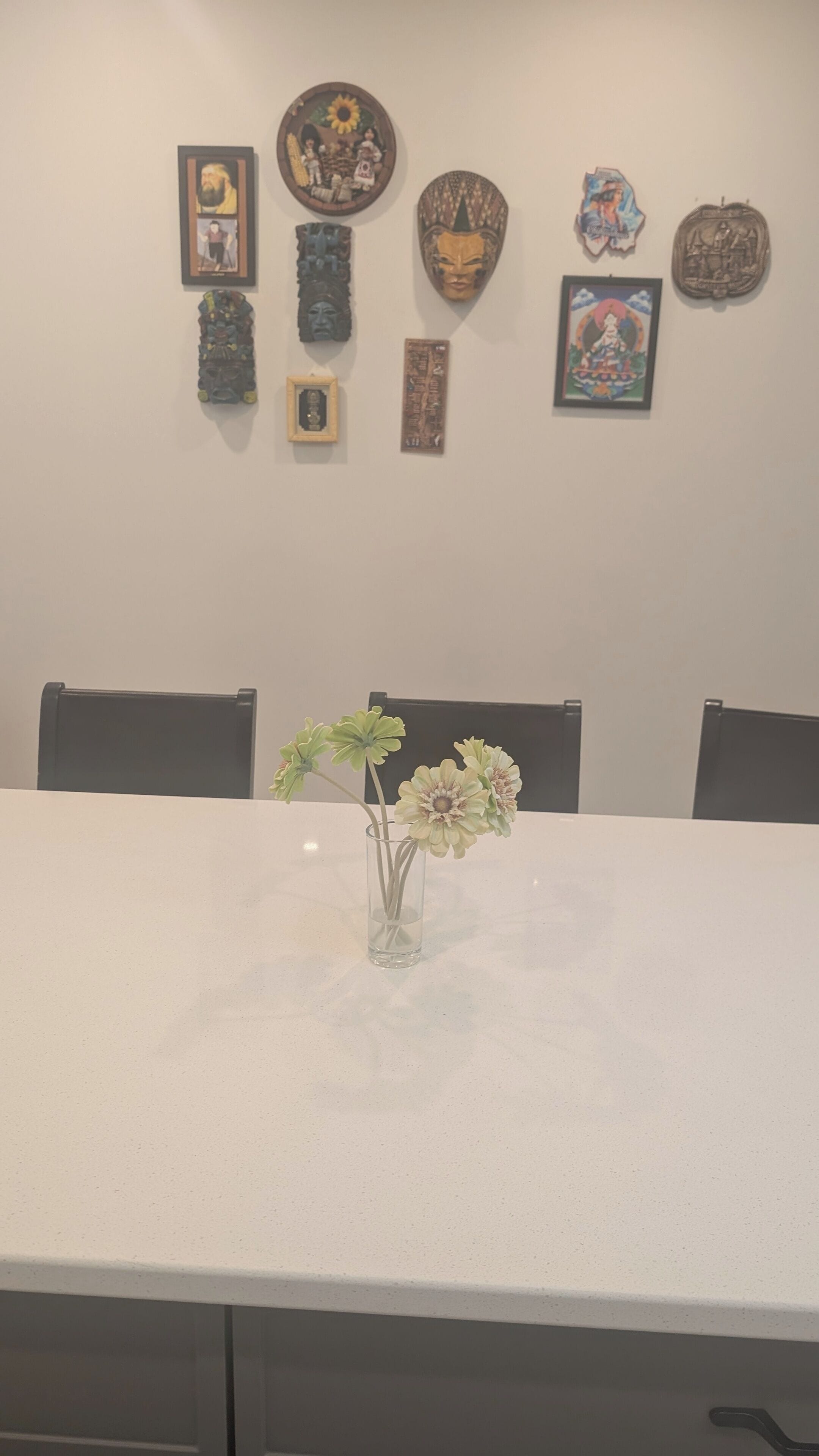A dining table with a vase of flowers, surrounded by chairs.