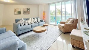 A modern living room with a sofa, two round coffee tables, and a wicker chair.