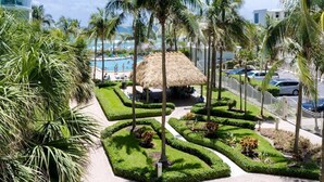 A resort with a pool, palm trees, and a thatched-roof structure.
