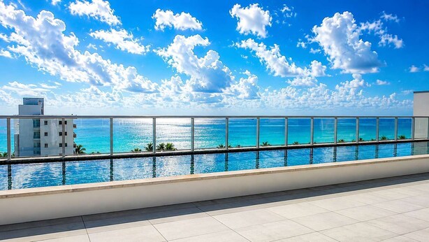 A rooftop pool with a clear view of the ocean and a building in the background.