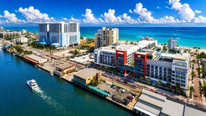 A coastal cityscape with high-rise buildings, a marina, and a beach.