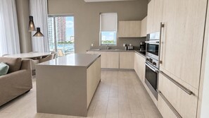 A modern kitchen with a central island, built-in appliances, and a view of a cityscape.