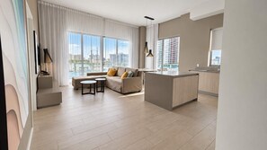 Apartamento moderno com sala de estar, cozinha e grandes janelas com vista para a cidade.