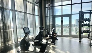 A gym with exercise equipment, large windows, and a view of the city.