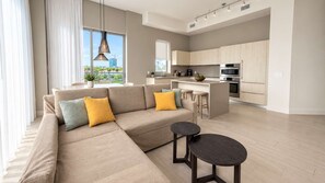 A modern living room with a sofa, two side tables, and a view of the city through large windows.