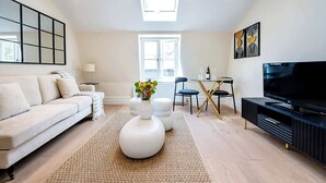 Un salon moderne comprenant un canapé, une table basse, un téléviseur et un coin repas.