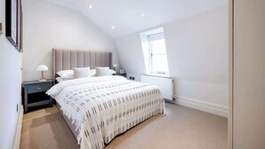 Une chambre moderne avec un grand lit, une table de chevet, une fenêtre et un luminaire au plafond.