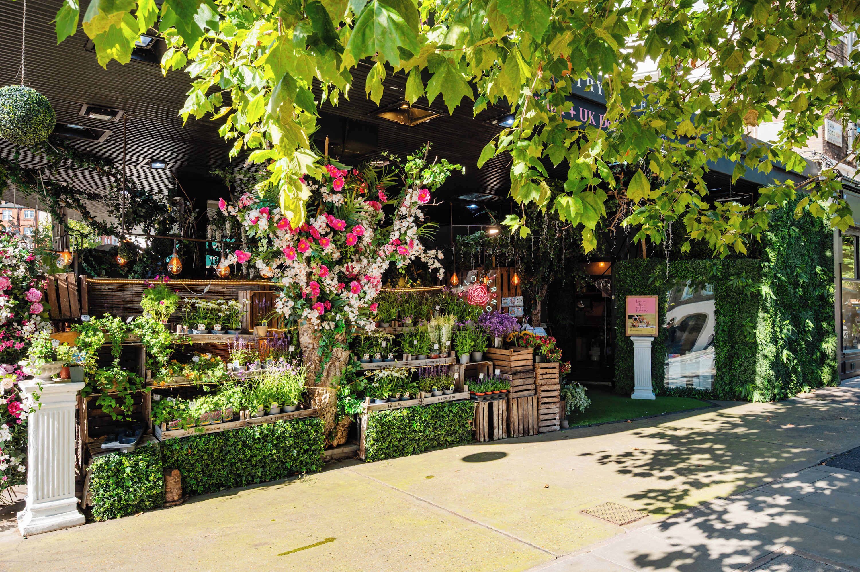 A flower shop with various plants and flowers displayed outside.