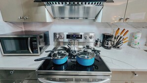 A kitchen with a microwave, stove, and pots.