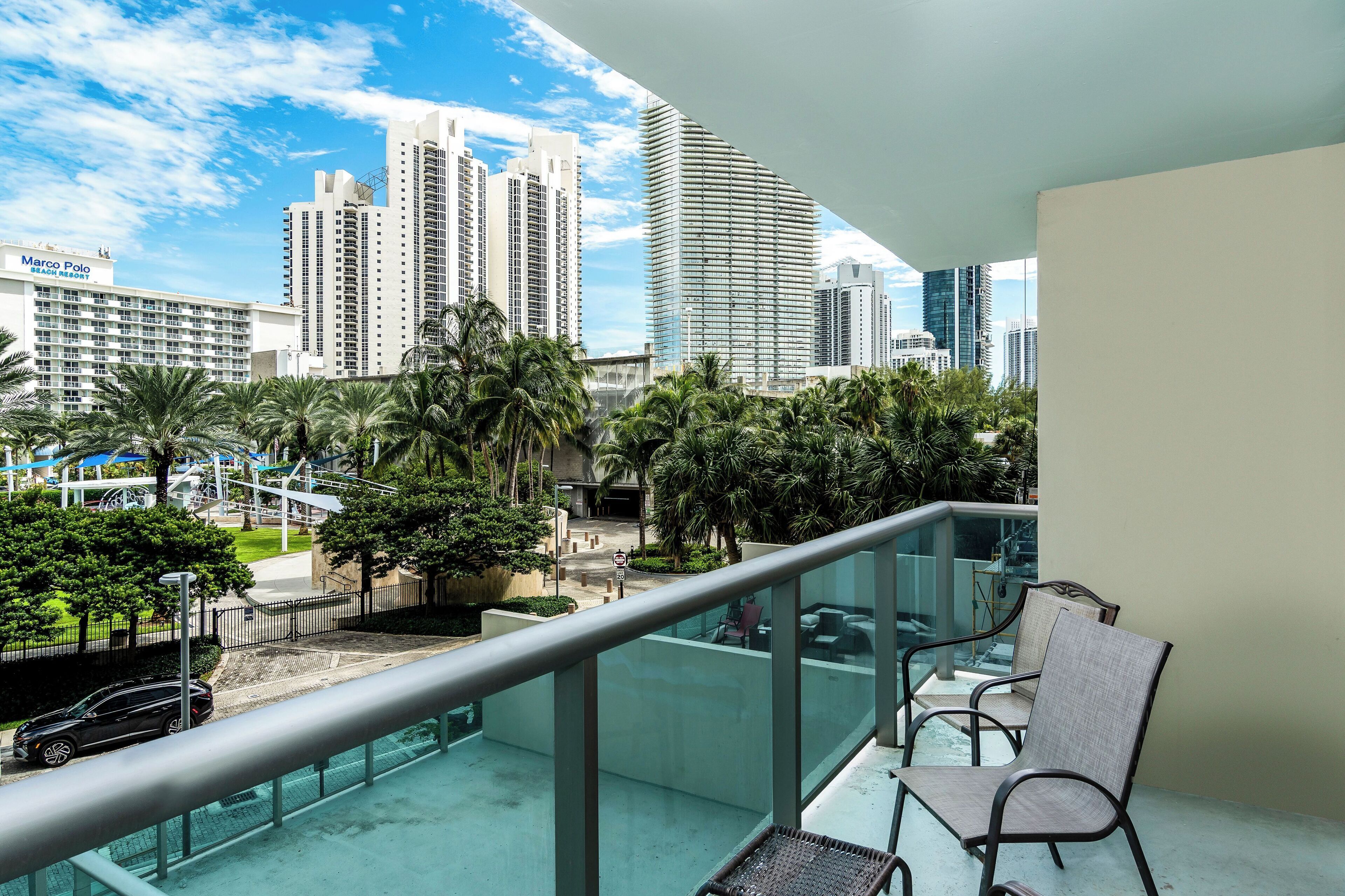 A balcony with a view of a cityscape, including a hotel named Marco Polo Beach Resort.