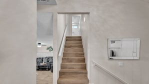 Un escalier menant à un deuxième étage, avec des marches en bois et des rampes blanches.