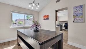 Une cuisine moderne avec un îlot central en bois foncé, une grande fenêtre et un luminaire suspendu.