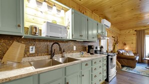 A kitchen with light green cabinets, a stainless steel sink, a microwave, and a coffee maker.