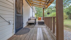 A covered porch with two wicker sofas, a wooden deck, and a string of lights.
