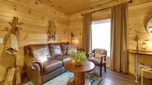 A cozy cabin interior with a leather sofa, a wooden coffee table, and a rustic decor.