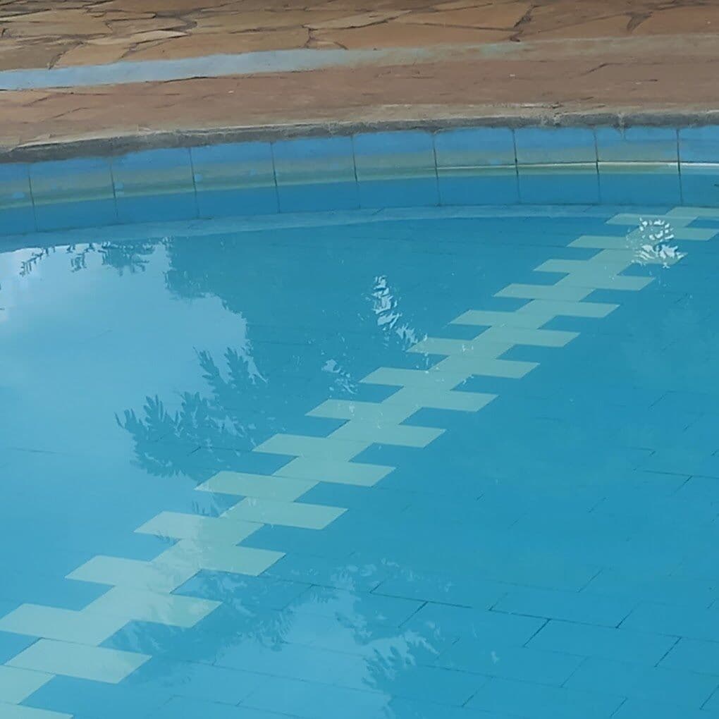 A swimming pool with a clear blue water surface and a tiled edge.