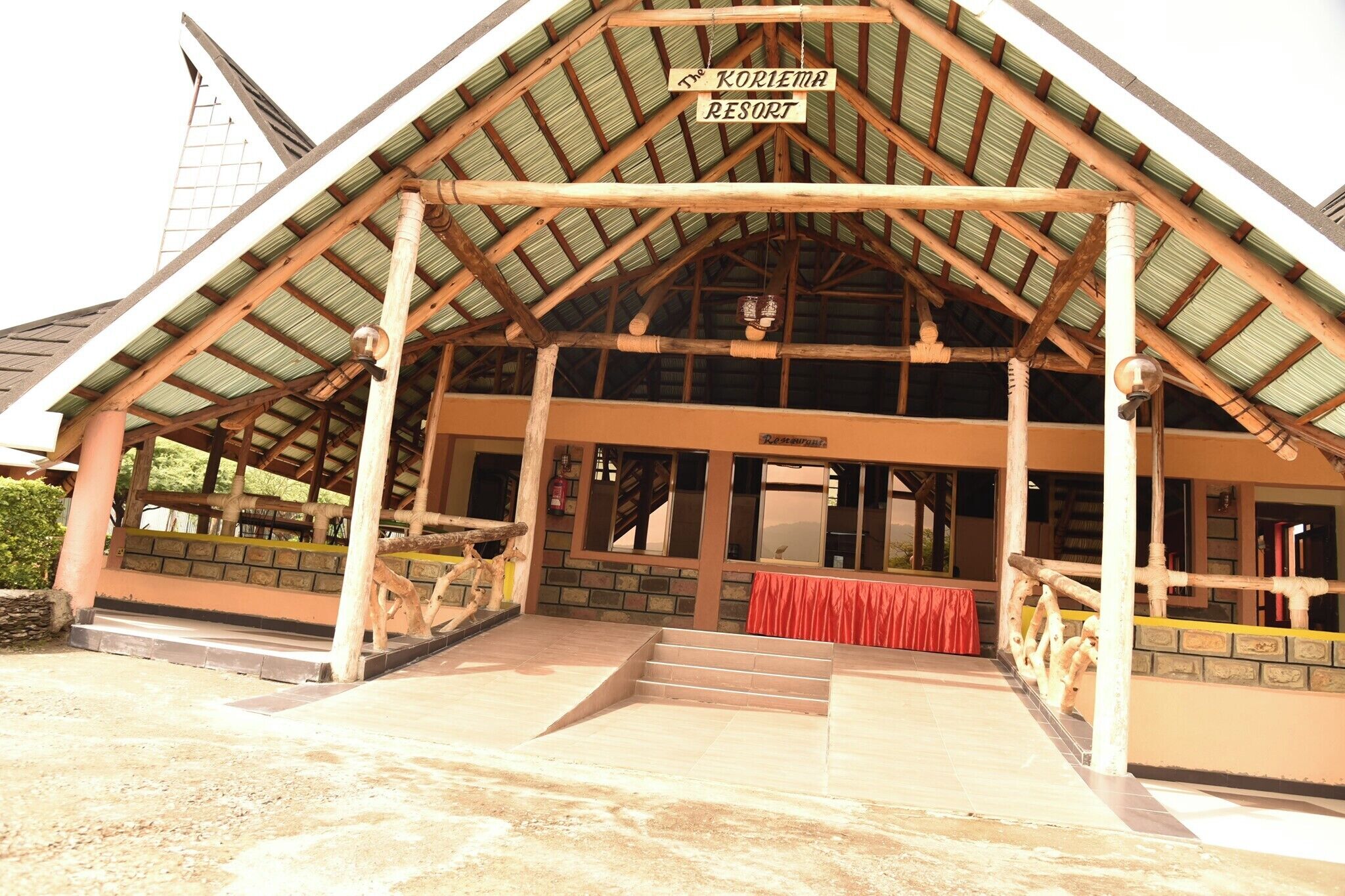 A resort entrance with a covered porch, wooden beams, and a sign reading 'The Koriana Resort.'