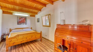 A bedroom with a wooden bed, a wooden dresser, and a window with a view.