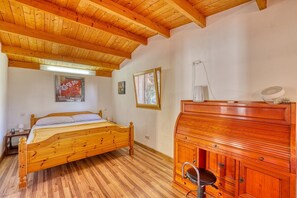 Ein Schlafzimmer mit einem hölzernen Bett, einer Holzkommode und einem Fenster mit Blick.