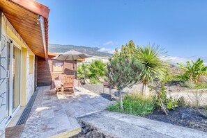 Une terrasse avec une table et des chaises, entourée de plantes et offrant une vue sur la montagne.