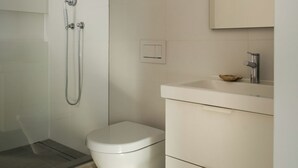 Une salle de bain moderne dotée d’une douche à l’italienne, de toilettes et d’un meuble-lavabo avec un miroir.