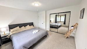 A bedroom with a bed, a nightstand, a mirror, and a wooden chair. - Brand New Large 2Bd/1Ba Apartment - Near Downtown, King Bed! (Anchorage)