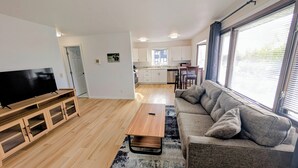 A modern living room with a flat-screen TV, wooden entertainment unit, and a grey sofa. - Brand New Large 2Bd/1Ba Apartment - Near Downtown, King Bed! (Anchorage)