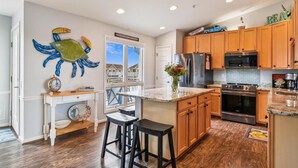 A kitchen with wooden cabinets, a large island, stainless steel appliances, and a view of houses through the window. - Entire Villa with Gorgeous Bay Views and 5 minute Walk to the Beach (Bethany Beach)