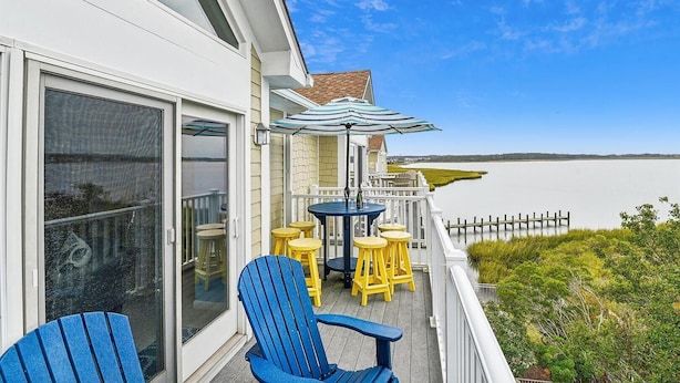 A balcony with a table and chairs, overlooking a body of water. - Entire Villa with Gorgeous Bay Views and 5 minute Walk to the Beach (Bethany Beach)