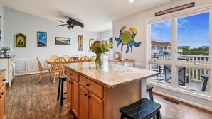 A kitchen with wooden cabinets, a marble countertop, and a large window overlooking a deck. - Entire Villa with Gorgeous Bay Views and 5 minute Walk to the Beach (Bethany Beach)