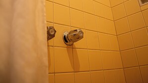 Um chuveiro com azulejos amarelos e um chuveiro.