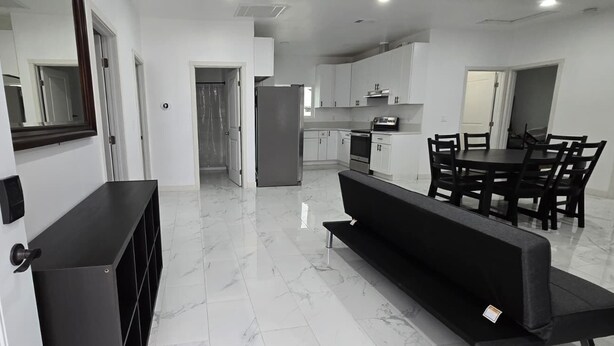 Una cocina moderna con armarios blancos, una mesa de comedor con sillas y un banco negro.