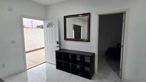 Un pasillo con una puerta blanca, una consola negra y un espejo en la pared.