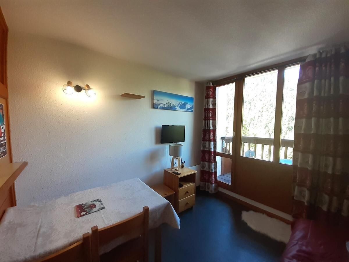 A room with a bed, a desk, a television, and a window with curtains.