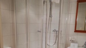 A bathroom with a glass-enclosed shower, a white sink, and a toilet. - Bellevue (Porrentruy)