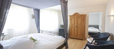 Un dormitorio con cama, armario de madera y dos sillas.