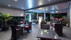 An outdoor patio area with tables and chairs, a potted plant, and a view of the garden. - Bellevue (Porrentruy)