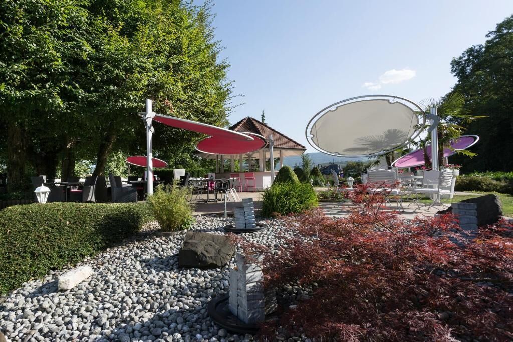 Un espace extérieur aménagé avec des tables et des chaises, entouré de rochers et de plantes.