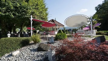An outdoor seating area with tables and chairs, surrounded by rocks and plants.