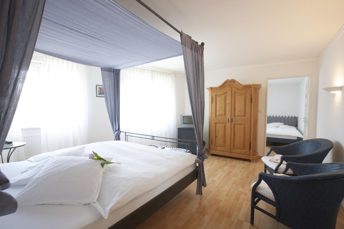 Quarto de hotel com cama, armário de madeira, uma cadeira e televisão.