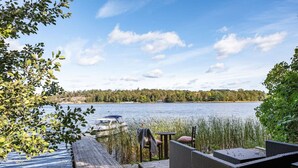 A lakeside deck with a boat docked, surrounded by trees and a clear sky.