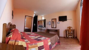 A bedroom with a bed, a desk, a chair, a TV, and a mirror. - Hotel San Angel Puebla (Puebla)